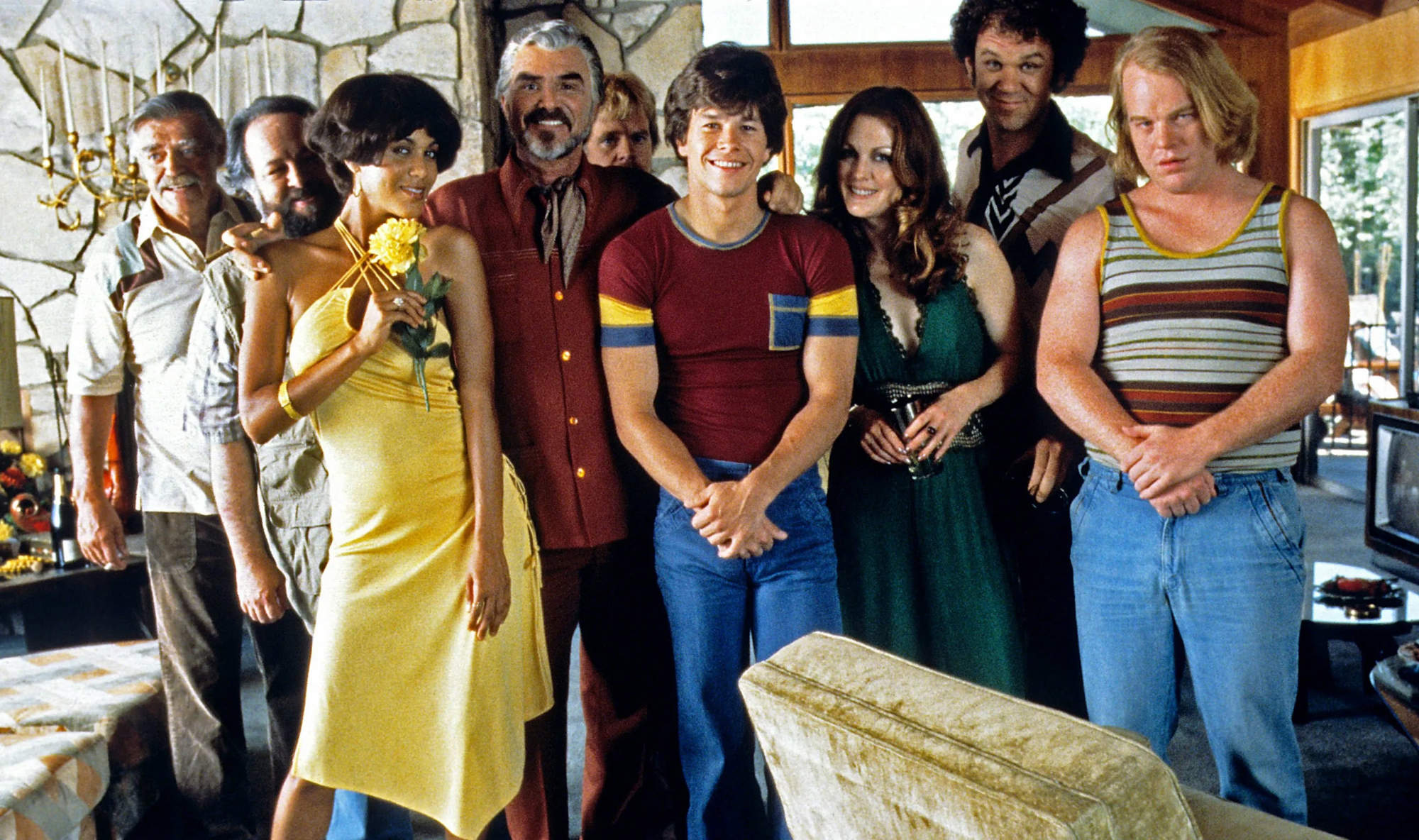 Grupo de personas vestidas años 70 posan ante la cámara en un salón.