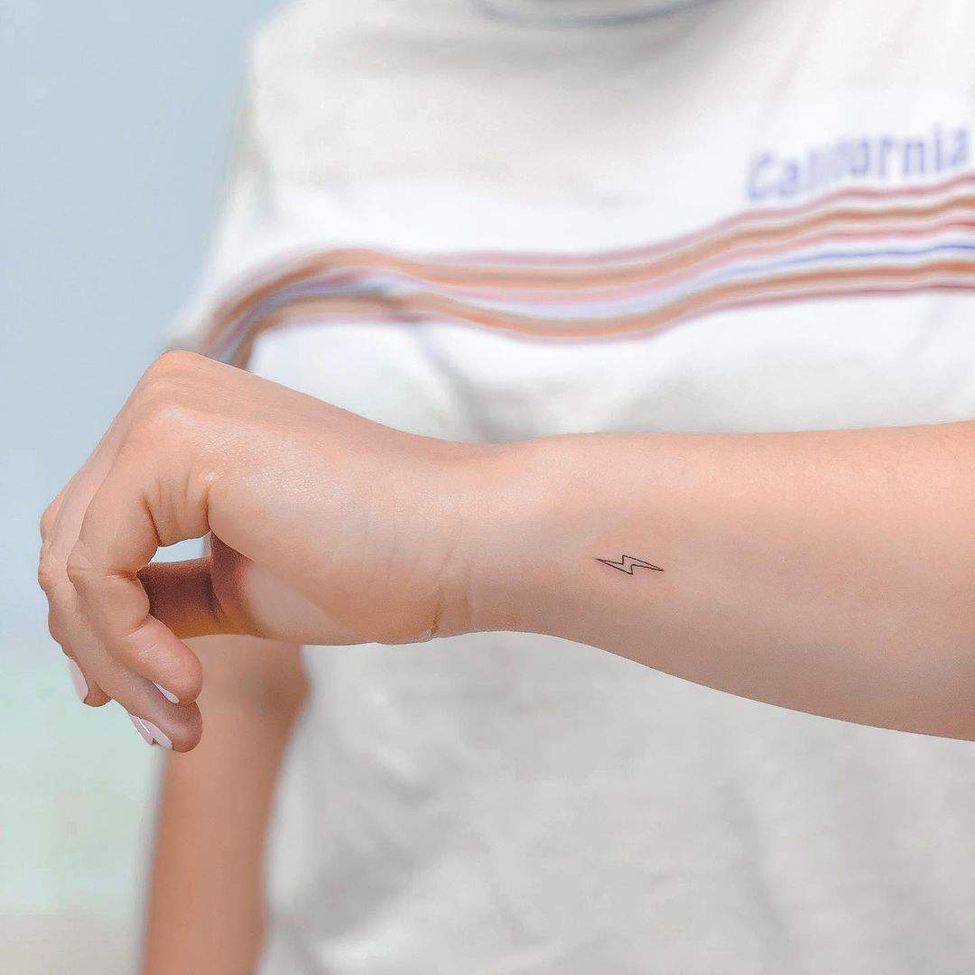 Un diminuto rayo tatuado en el antebrazo