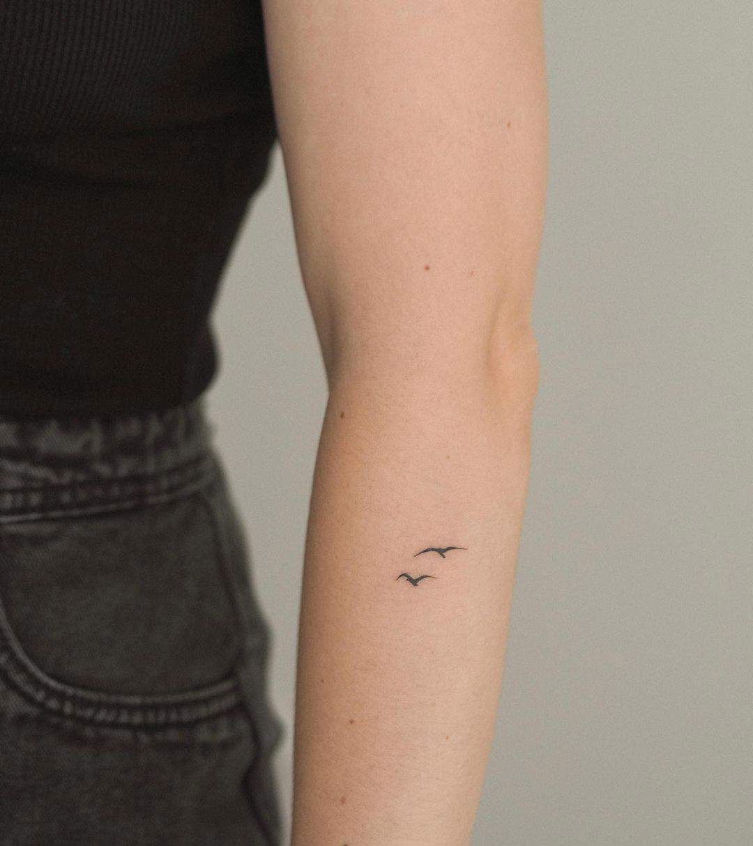 Dos diminutos pájaros tatuados en el antebrazo