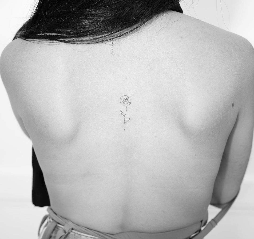 Tatuaje fine line de una rosa en el centro de la espalda