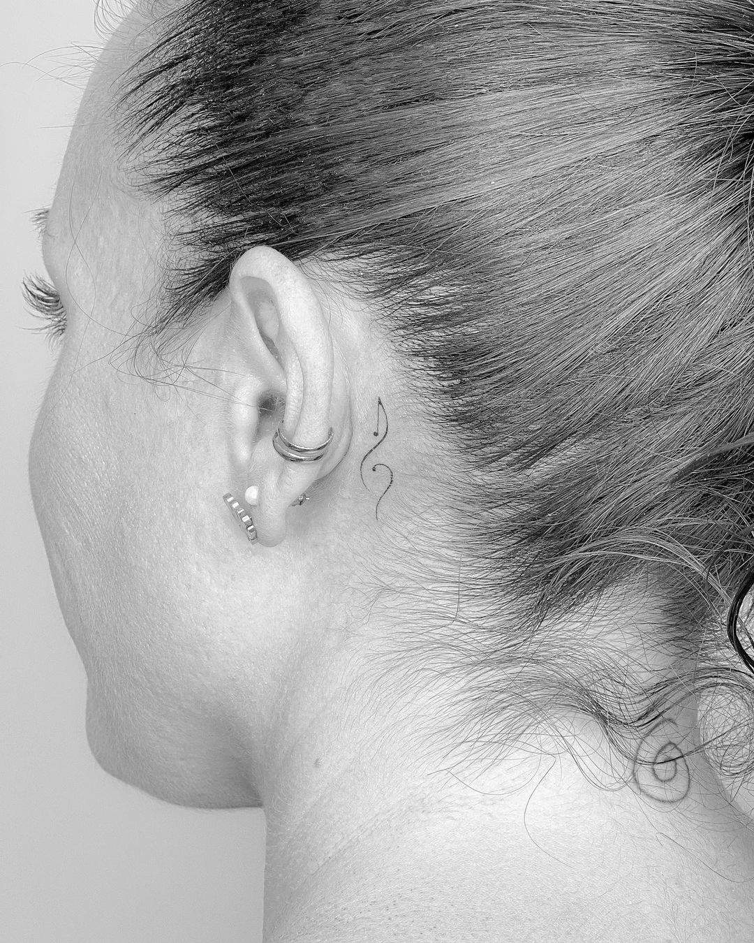 Clave de sol tatuada tras la oreja