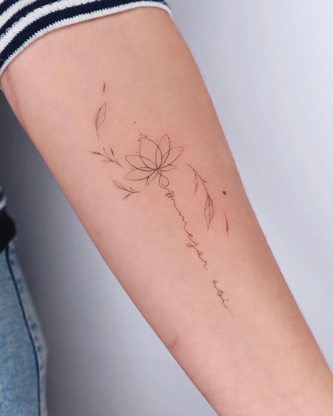 Una flor de loto y una frase tatuadas en el antebrazo