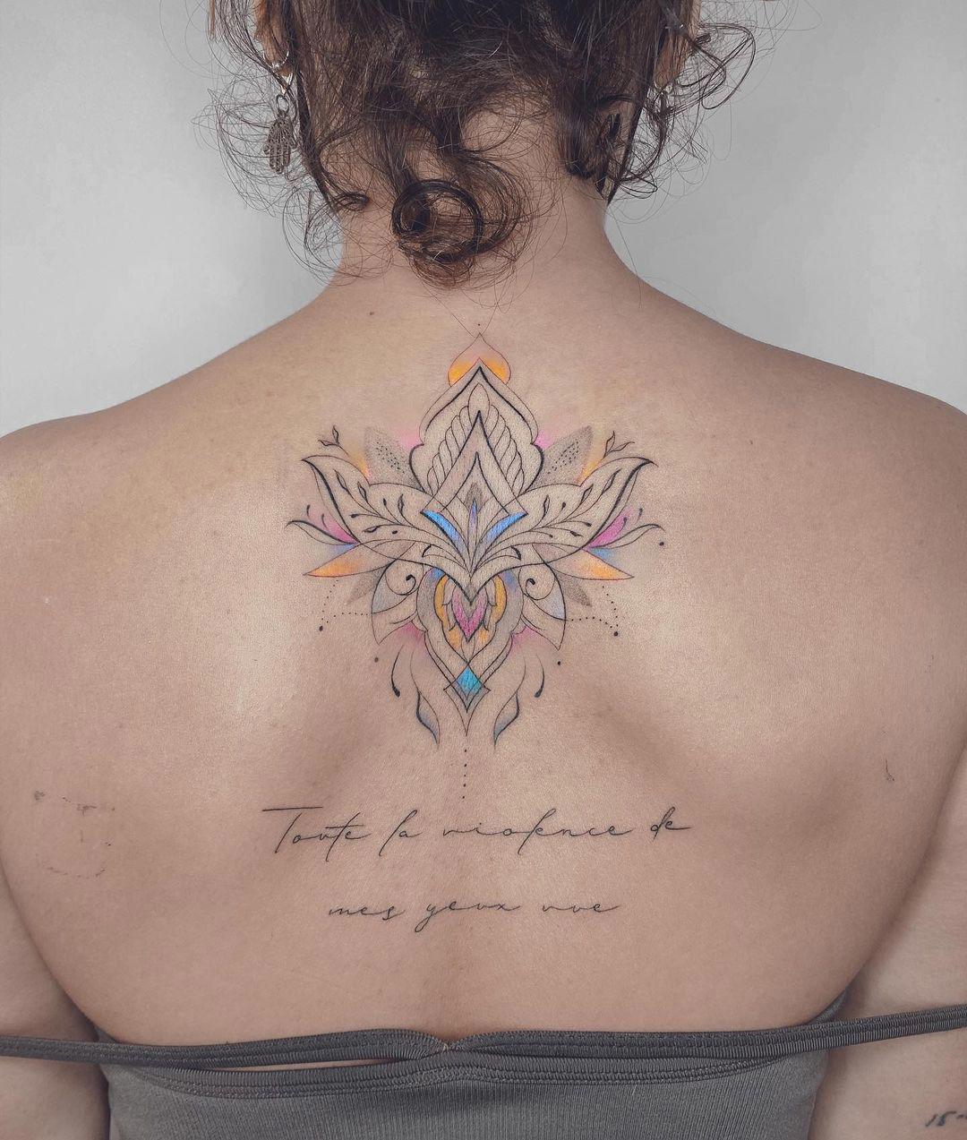 Tatuaje de flor de loto con frase en la espalda