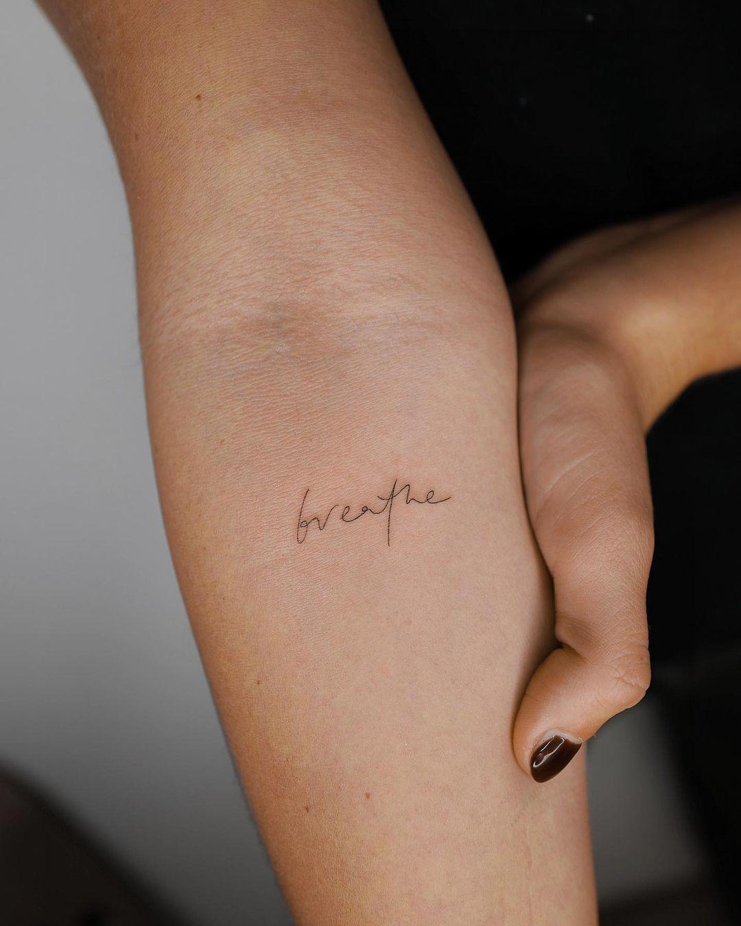 Palabra 'breathe' tatuada en letra fina