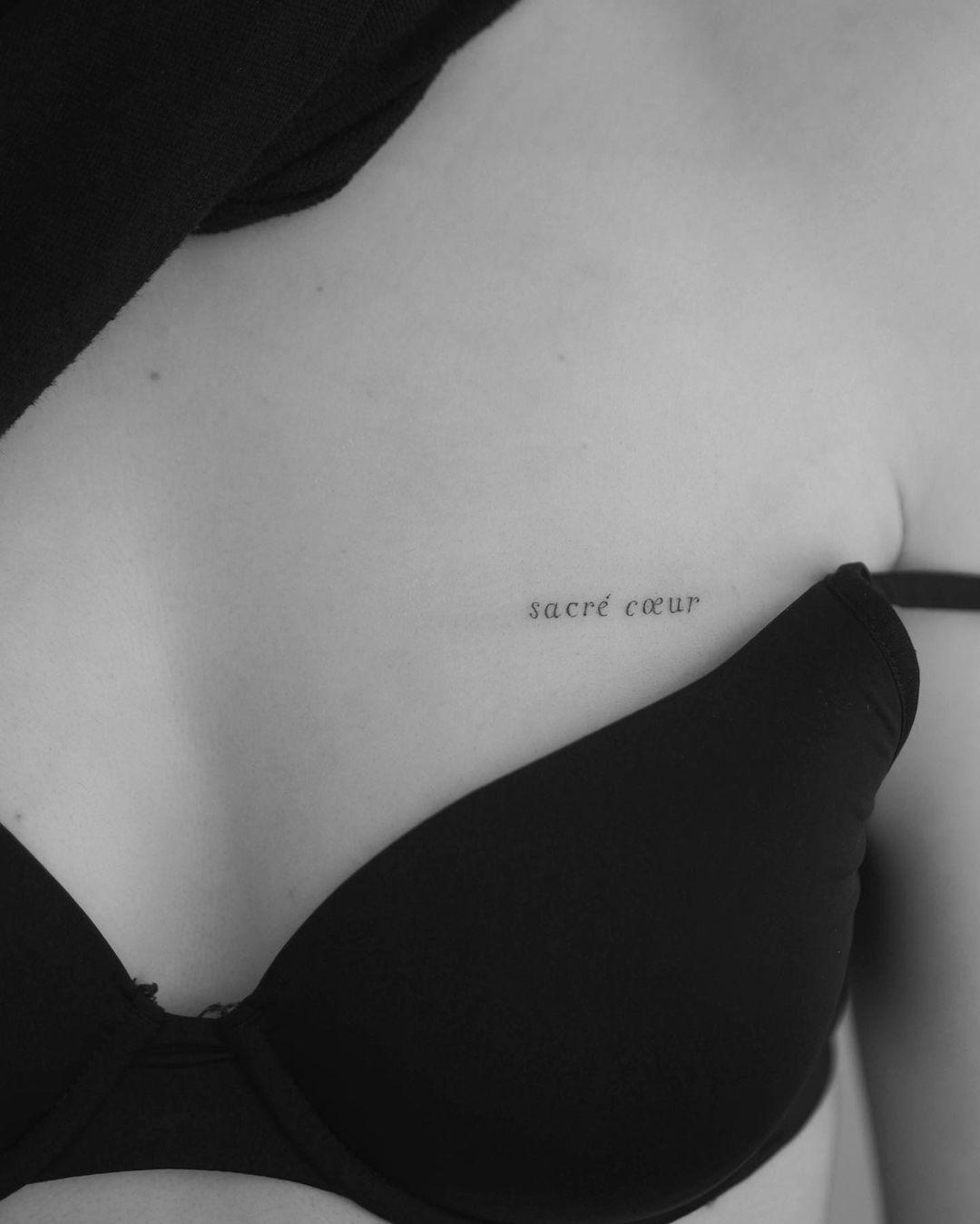 'Sacré coeur' tatuado con letra serif sobre el pecho