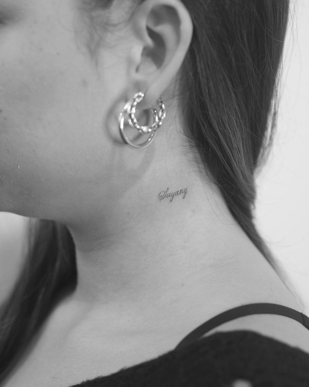 Palabra tatuada con tipo de letra serif en el cuello