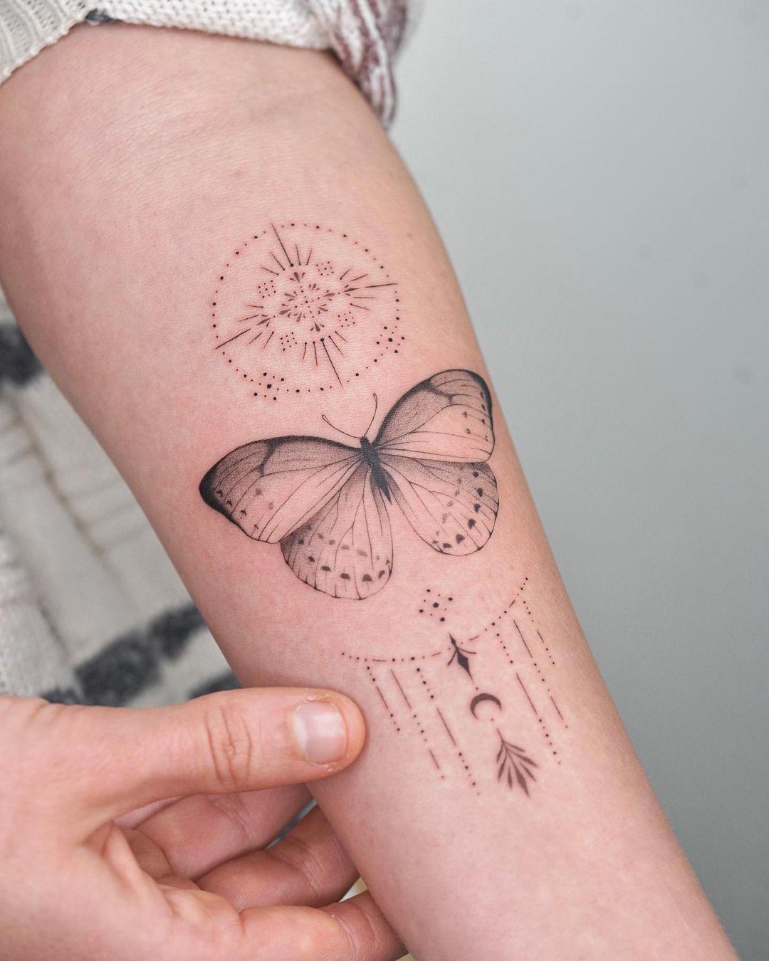 Una mariposa tatuada en el antebrazo con ornamentación