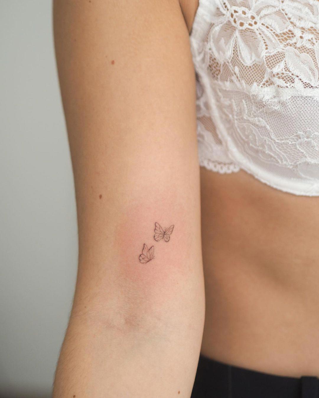 Dos mini mariposas tatuadas en el brazo