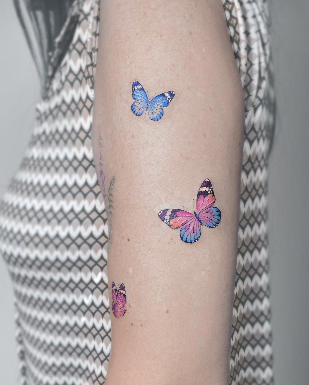 Tres mariposas tatuadas sobre el brazo