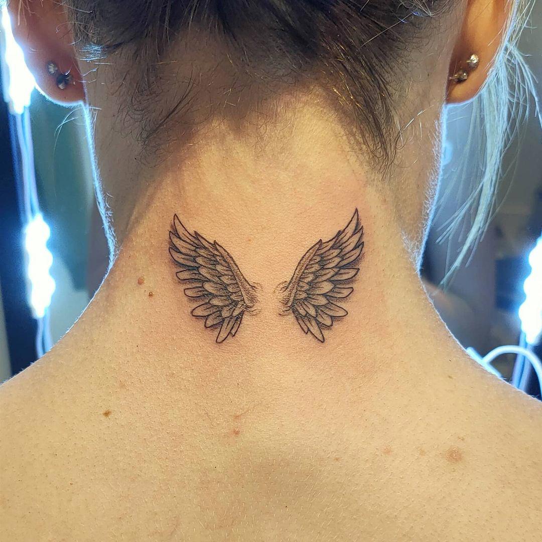Dos alas de estilo realista tatuadas en el cuello