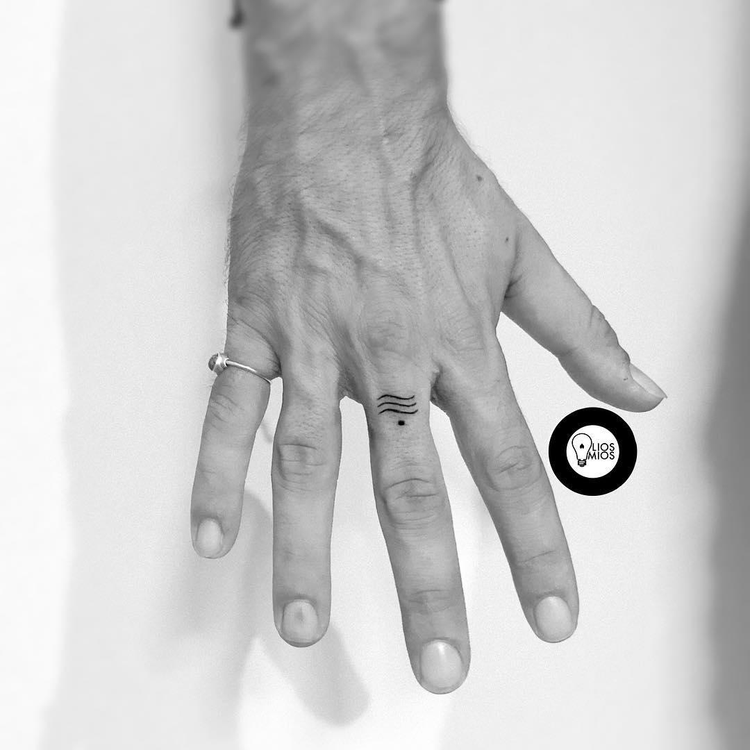 Símbolo tatuado en el dedo corazón