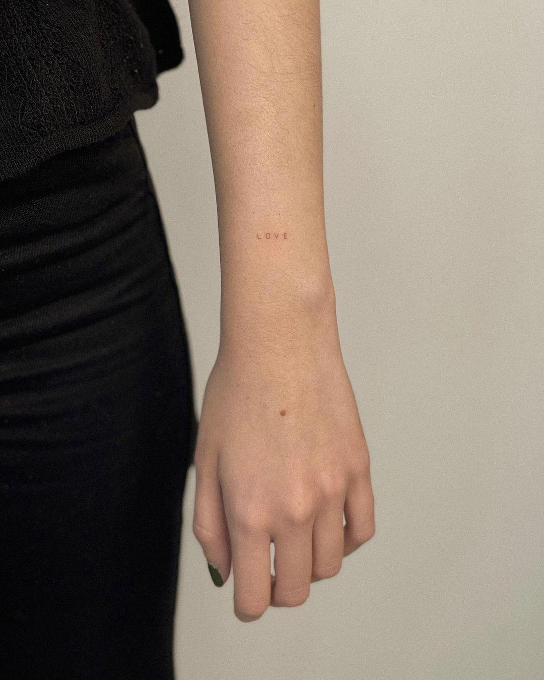 Palabra ‘fine line’ tatuada en el antebrazo