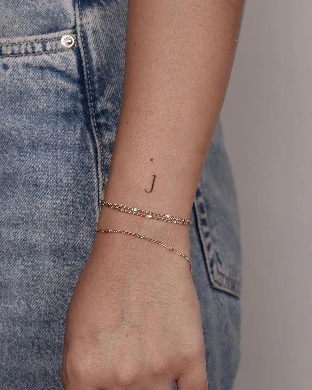 Tatuaje de una J en el antebrazo