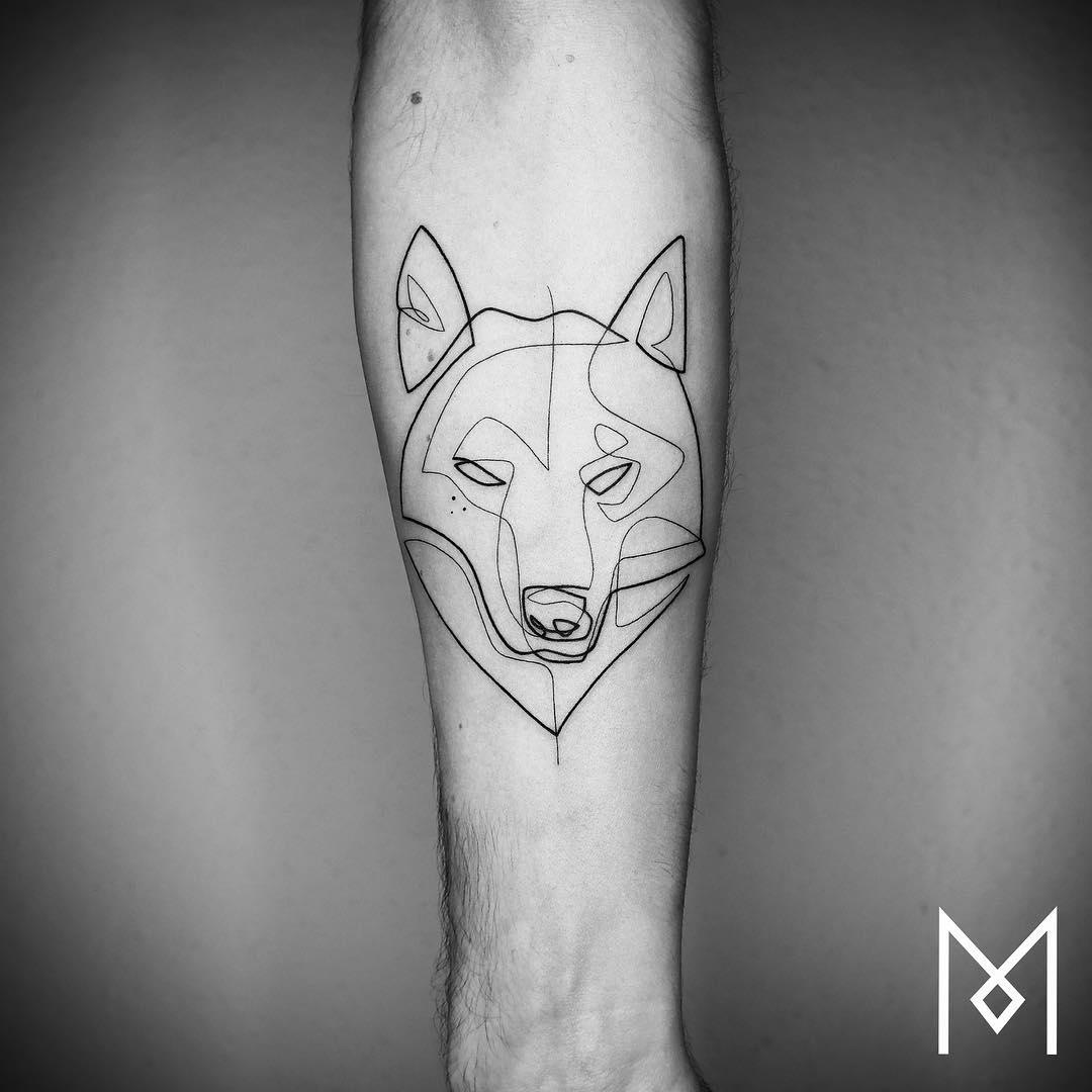 Tattoo minimal de cabeza de lobo en el antebrazo