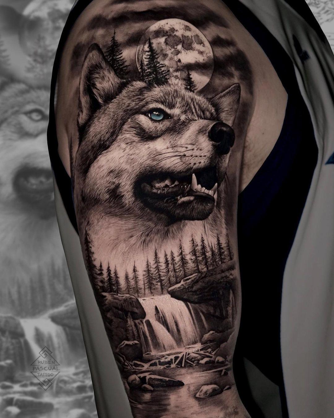 Tattoo de lobo y paisaje en la parte alta el brazo