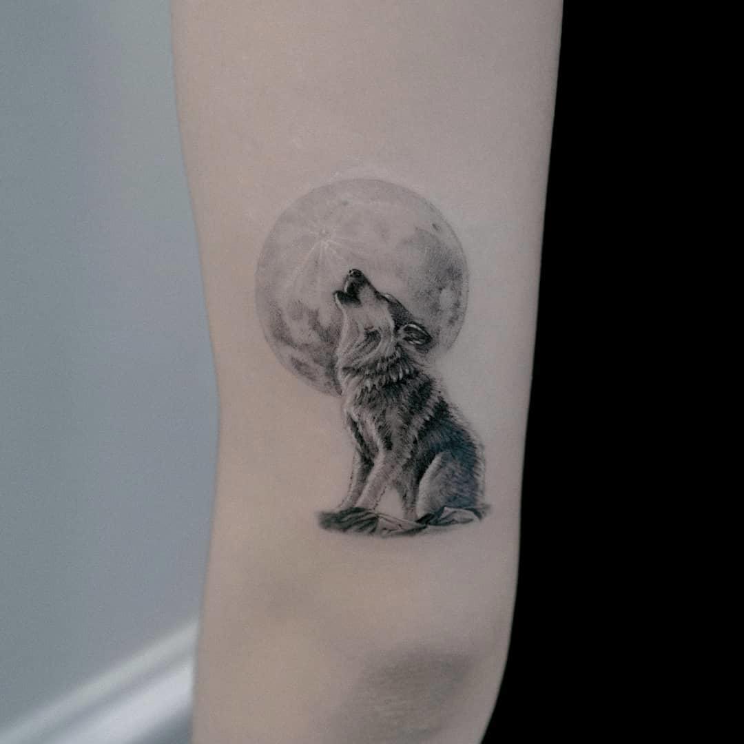 Tatuaje de lobo y luna en el brazo
