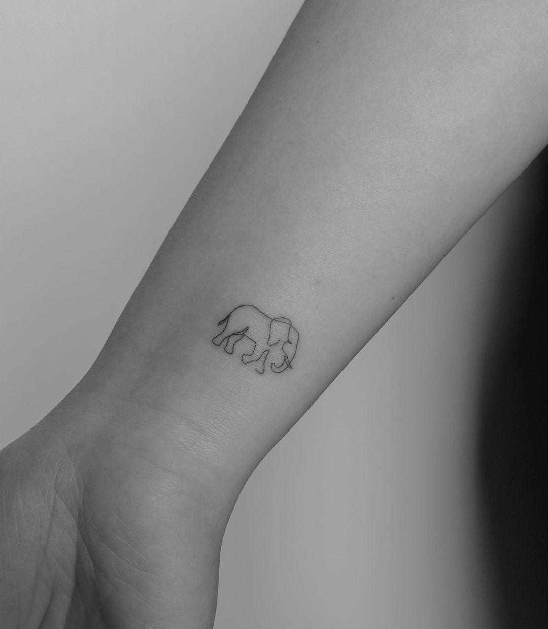 Un elefante de trazo fino tatuado en la muñeca
