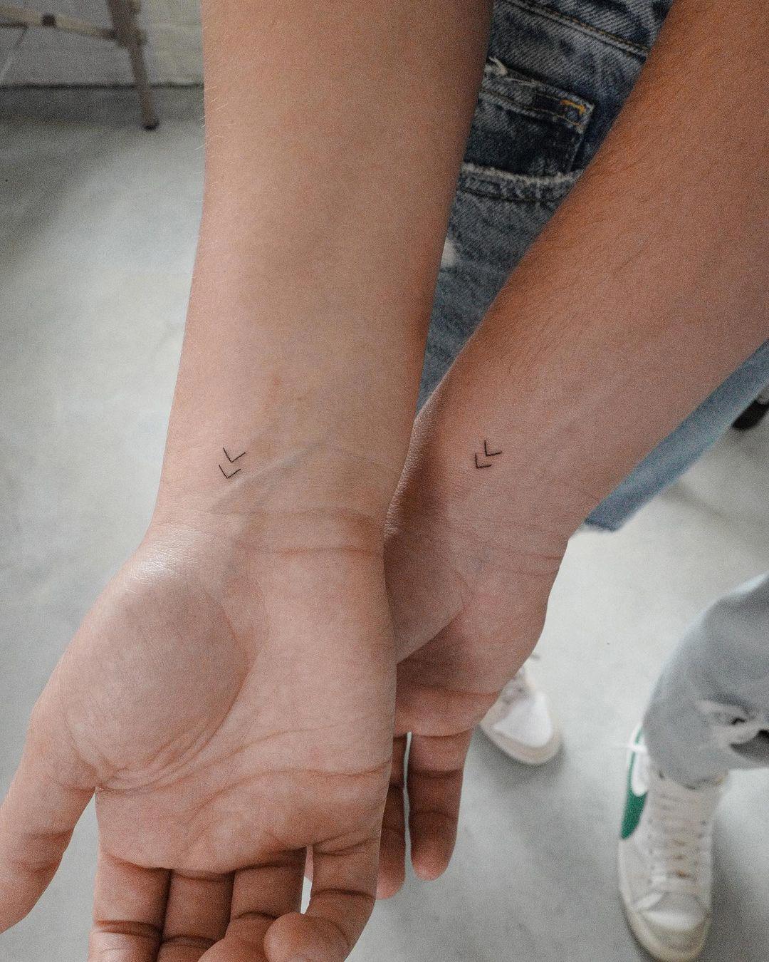 Dos flechas minimalistas tatuadas en la muñeca